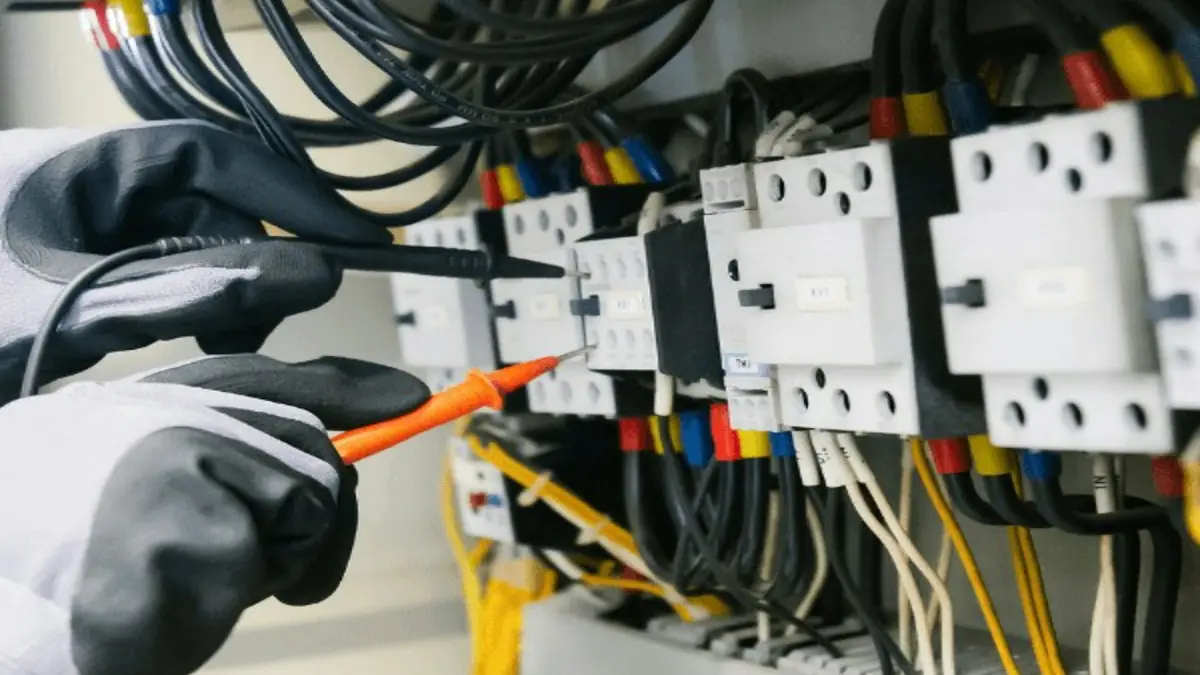 Pengujian panel listrik dengan alat ukur dan APD yang sesuai.